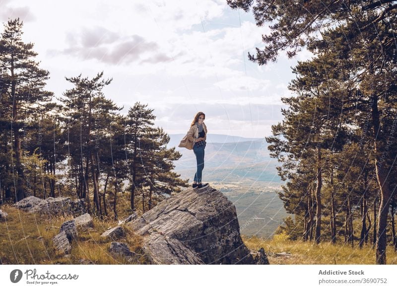 Traveling woman on stone in forest rock tourist mountain vacation traveler adventure trip female destination holiday freedom stand relax enjoy admire recreation