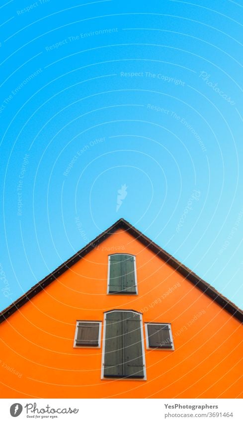 Orange house against blue sky. House with orange walls minimalist. German architecture Germany abstract antique attic bottom-up bright building clear colors