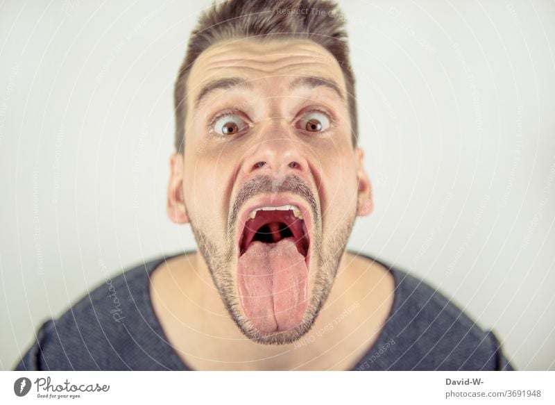Man looks crazy into the camera with open mouth Mouth wide open Tongue Crazy Profile Face loopy portrait mouth opened Open lick show tongue
