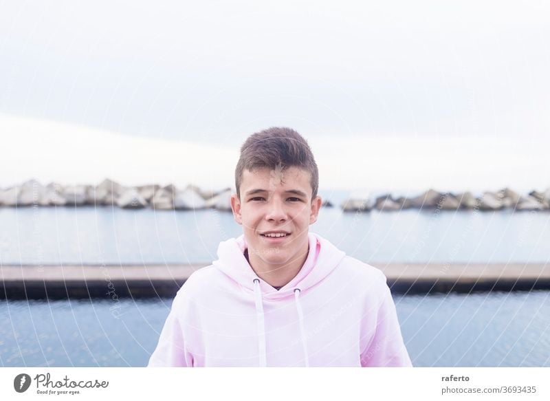 Young teenager male standing on rock breakwater while looking at camera young 1 smiling breakwaters photogenic casual attire person adult happy cool man