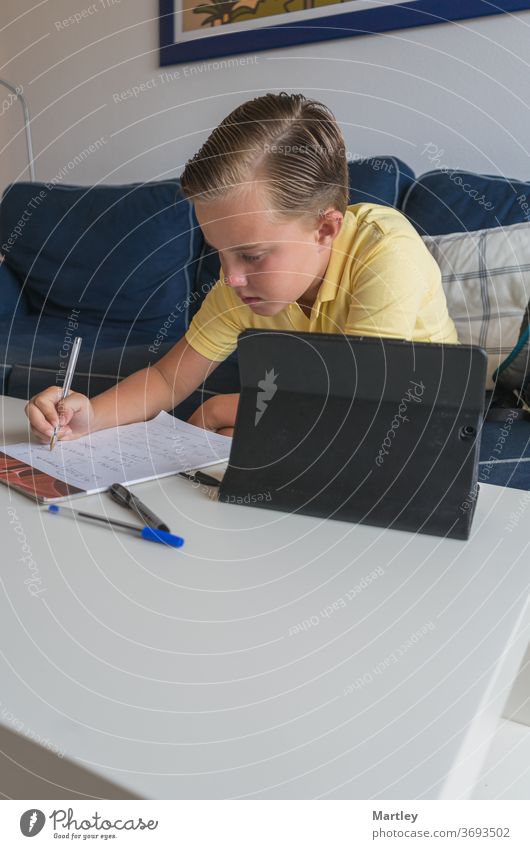 Little boy online with his classmates during video conference call, doing his work on a notebook and sharing his math work. homework at home electronics