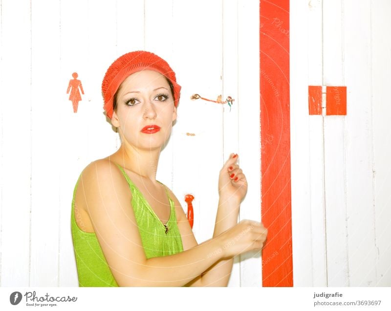 The girl with the beautiful red bathing cap and green swimsuit is flashed in front of the changing room. A summer love. Girl Woman Swimwear Bathing cap Swimsuit