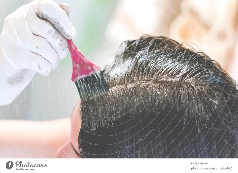 a young brunette caucasian woman dying her hair with a pink brush using white gloves at her home beauty dye paint professional attractive care fashion female