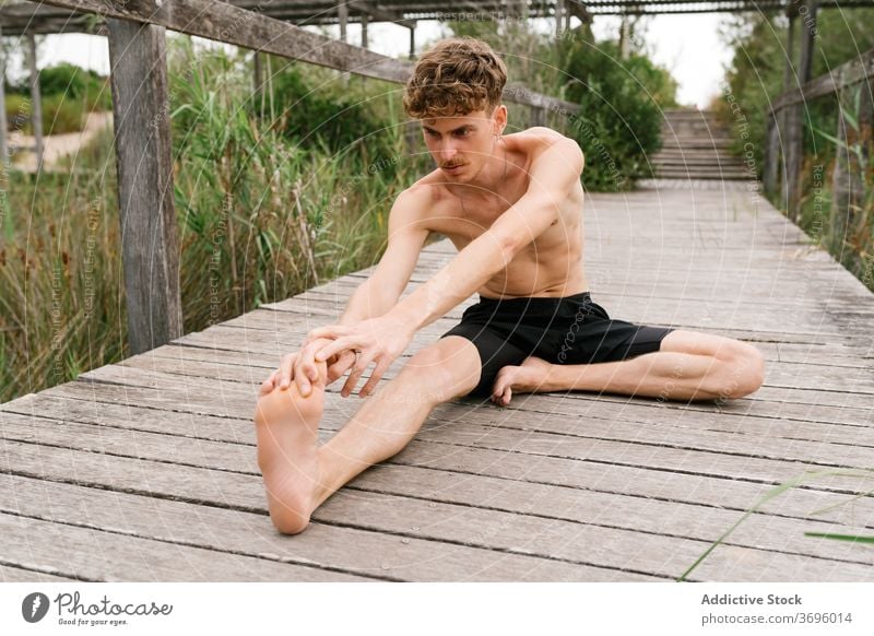 A young man with bare torso sitting in the lotus position Stock