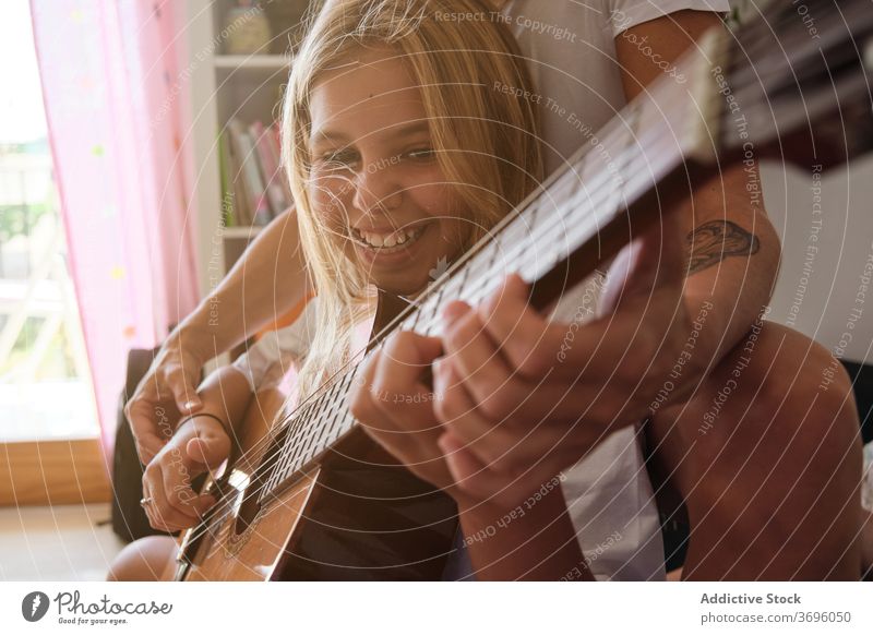 Smiling girl and a woman playing guitar in a house music teacher education learning student teaching lesson instrument musician performance pupil study class