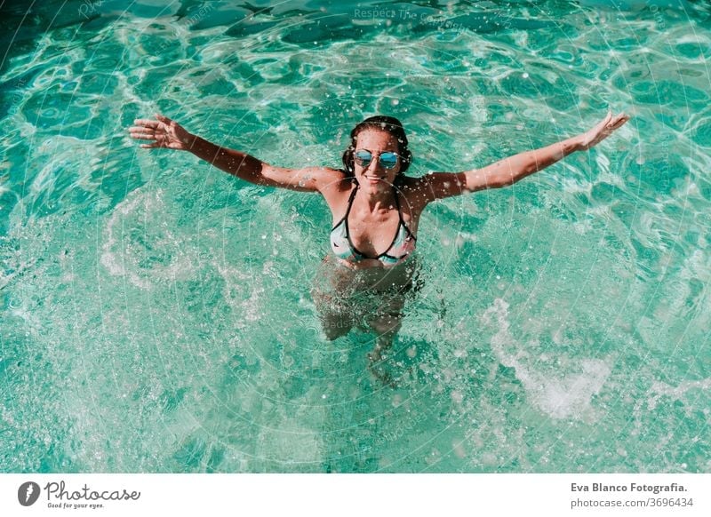 happy woman at the pool having fun splashing water. Summer and lifestyle one swimming pool sunglasses summer blue water hot playing laughter float party