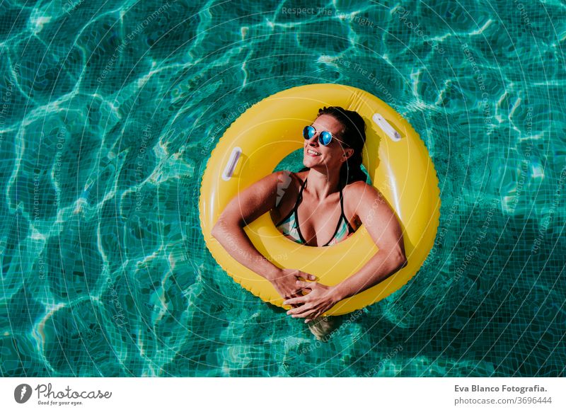 top view of happy young woman floating in a pool in a yellow donuts. summer and fun lifestyle inflatable swimming bubbles caucasian dive clear health light