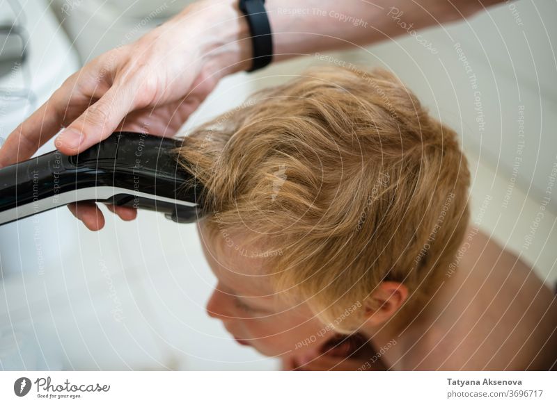 Father making haircut for son at home hairstyle child care machine bathroom family hand hairdresser man trimmer face young quarantine head caucasian male people