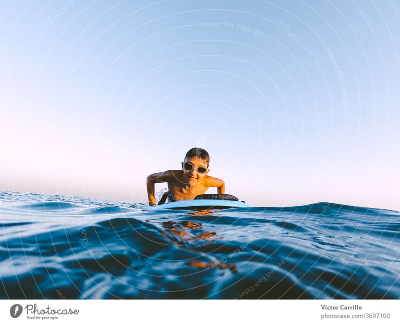 A young boy learning in body board outdoors in the shoreline in a sunny day of summer bodyboarder child holiday vacation leisure lifestyle surfboard surf-riding