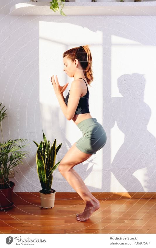 Tranquil woman doing yoga in Awkward pose awkward pose mindfulness practice home asana utkatasana tranquil female harmony healthy cozy room peaceful zen calm