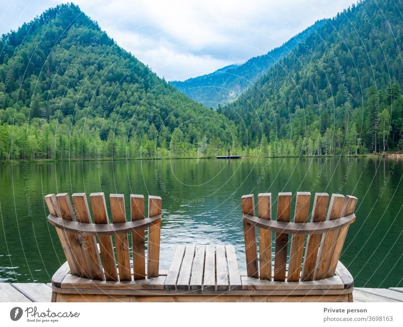 Two empty wooden deck chairs on the beach, beautiful landscape of mountain lake, vacation in the mountains, luxury summer vacation concept. nature calm travel