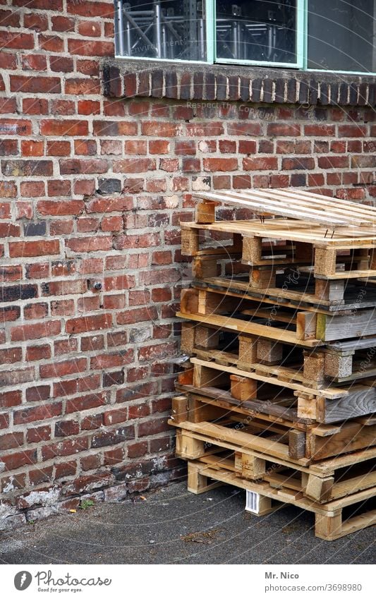 A stack of one-way pallets is standing in front of a building Palett pallet stacks Wall (barrier) built wood Window Workplace Logistics Warehouse