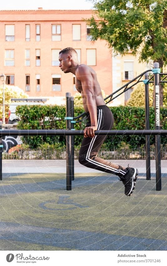 Muscular black sportsman doing pull ups training strong exercise athlete stamina naked torso workout male ethnic african american intense fitness sportswear