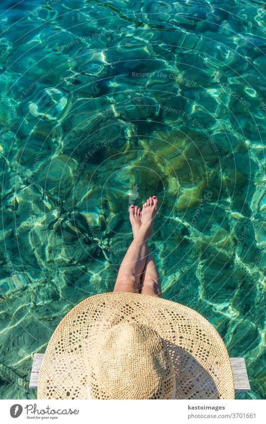 Graphic image of top down view of woman wearing big summer sun hat relaxing on small wooden pier by clear turquoise sea water leisure beauty girl person blue