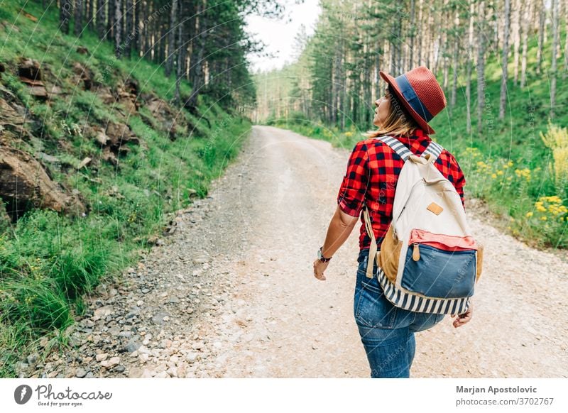 Young female nature explorer walking on mountain dirt road active adventure alone backpack discovery enjoy forest free freedom gravel green healthy hike hiker
