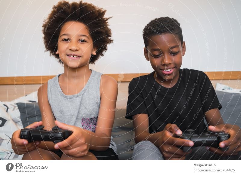 Two brothers playing video games at home. together controller african-american look indoors kids entertainment activity cheerful fun portrait boy ethnic family