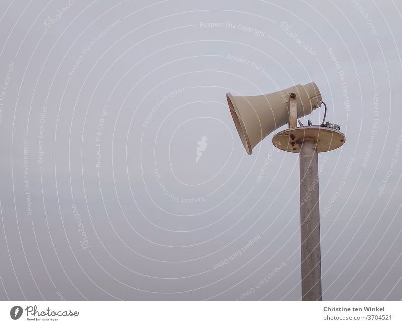Side view of an older loudspeaker in the shape of a megaphone in front of a hazy sky Loudspeaker Megaphone Pole Sky Communicate announcement Information