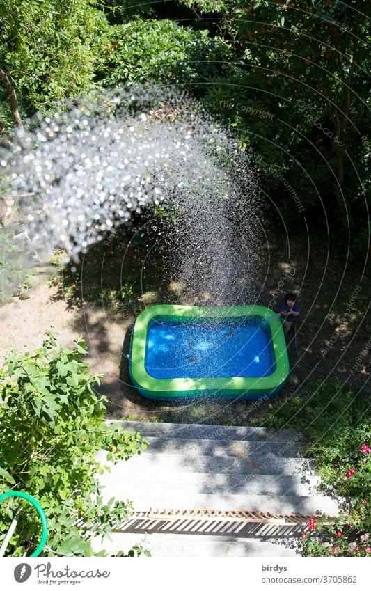A paddling pool in the garden which is filled from the balcony.  Water jet Paddling pool Jet of water Summer ardor cooling Drops of water Refreshment Sunlight