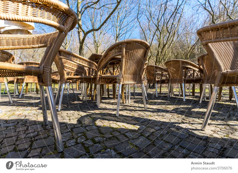 empty wicker chairs of a cafe on the terrace, outside table furniture restaurant nobody outdoor seat street leisure outdoors armchair rattan cobblestone trees