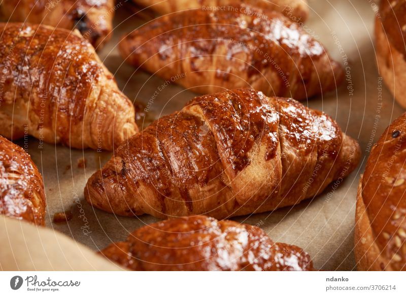 baked croissants in a baking sheet on brown parchment paper, delicious and appetizing pastries crispy crust cuisine bakery bread breakfast bun closeup dessert