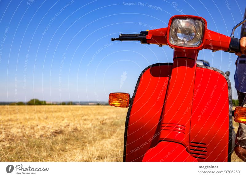 classic scooter on a wide field with drying grass in the heat of summer with copy room on the left Scooters Transport retro style Motorcycle no people