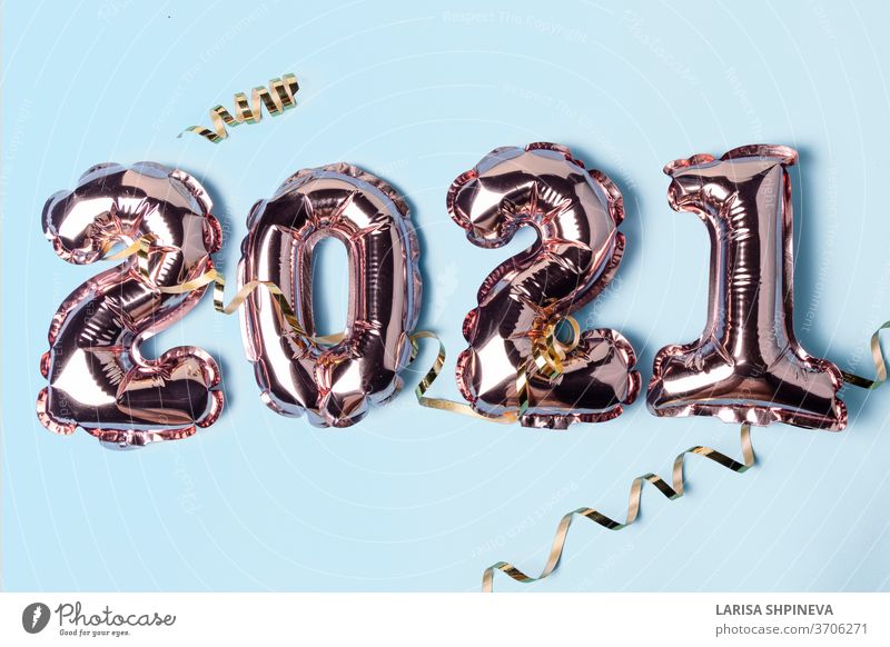 Gold pink balloons in form of numbers 2021 whis golden serpentine on blue background. Happy New Year celebration. Flat lay, top view eve party foil parkle