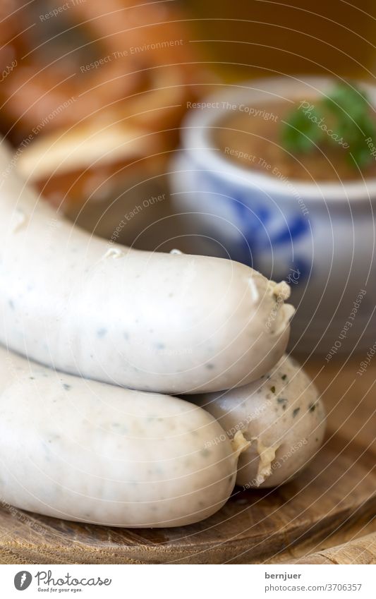 three Bavarian white sausages with mustard White sausages Veal sausage Salty Rustic traditionally Pretzel Wooden table Eating Mustard Sweet Parsley Meal