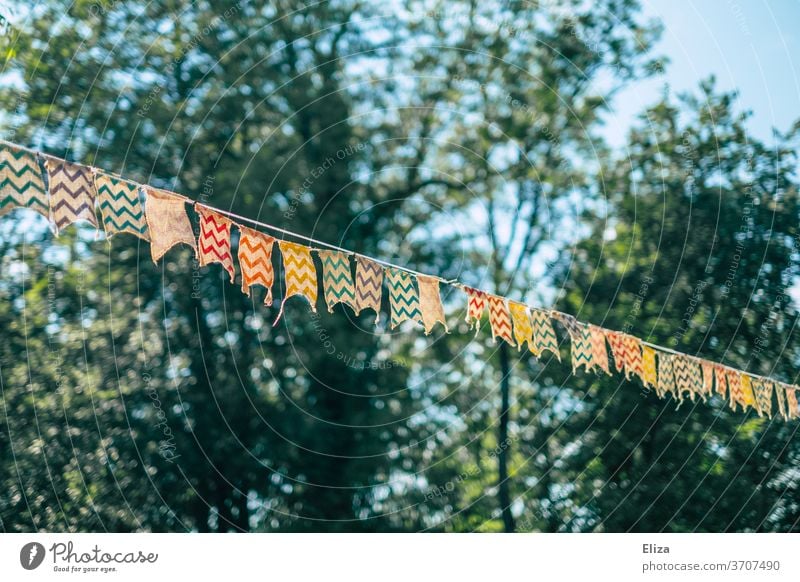 A colourful pennant chain between trees at a garden party Party bung Adorned Decoration Birthday Childrens birthsday Paper chain Feasts & Celebrations Embellish