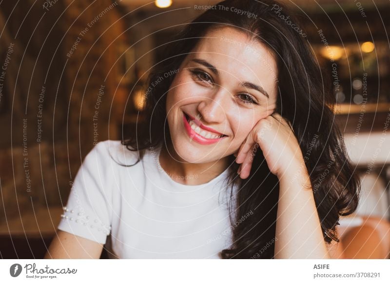 Portrait of a beautiful cheerful girl in a cafe looking at you young woman portrait happy smile person joy bar people toothy face close up brunette spanish