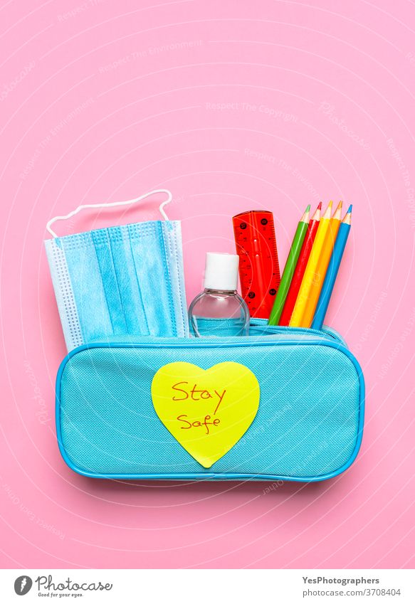 Pencil case with face mask, sanitizer and crayons. School supplies with stay safe message back back to school background blue care concept copy space corona