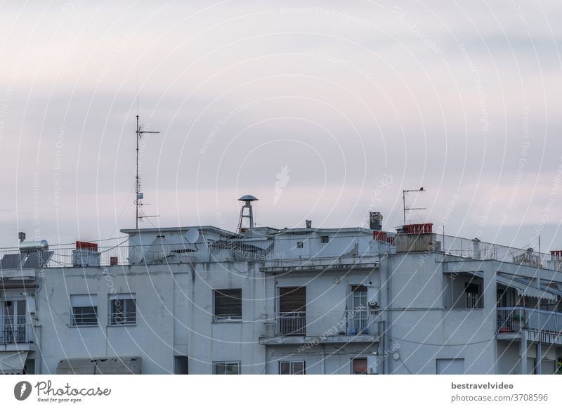 War air raid siren on residential buildings rooftop. Evening view of old mushroom shaped attack warning siren, between antennas and satellite dishes on top of city houses in Thessaloniki, Greece.