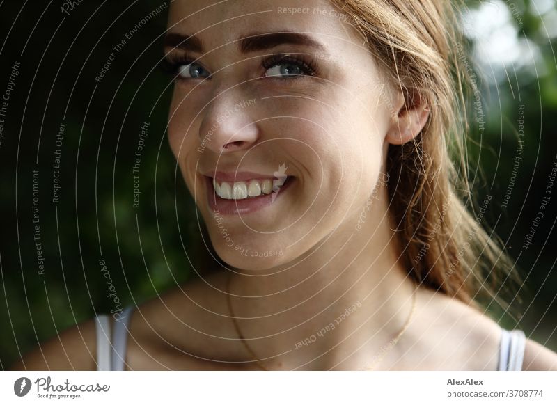 Close portrait of a young woman with cheek dimples in nature Light Athletic Feminine Emotions emotionally Looking into the camera Central perspective