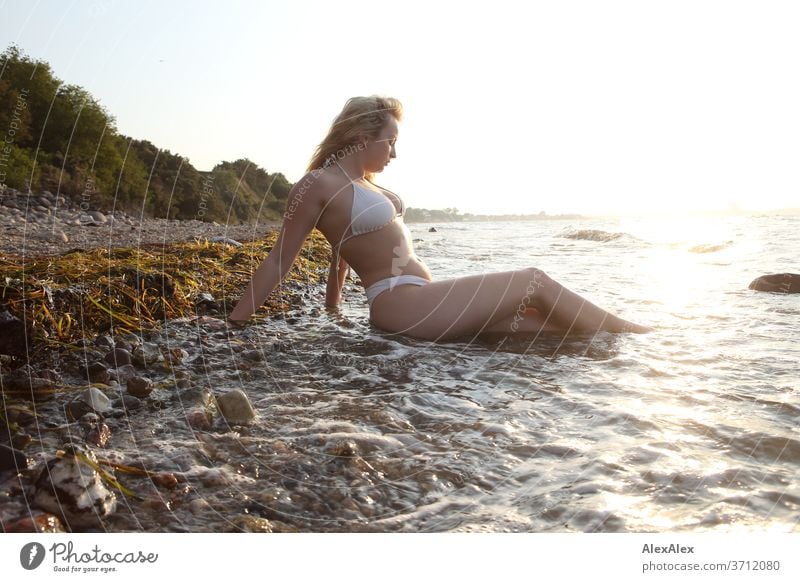 Young blond woman wearing bikini at the beach and looking at camera - a  Royalty Free Stock Photo from Photocase