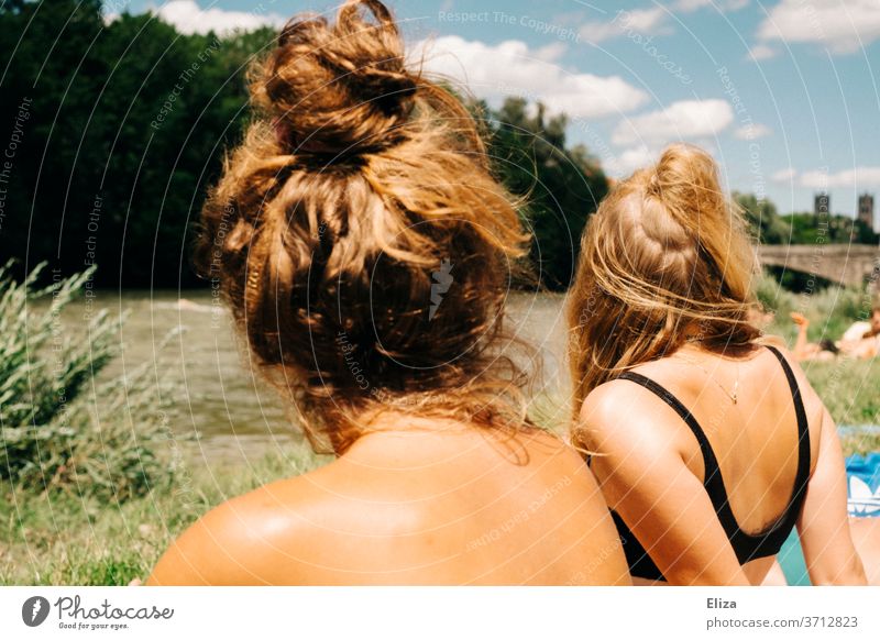 Two young women in bathing suits sunbathing by a river in summer. Summer Young women summer atmosphere Woman Sun River bathe Swimwear Bikini Blonde Girl