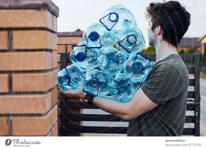Young man throwing out empty used plastic water bottles into trash bin. Collecting plastic waste to recycling. Concept of plastic pollution and too many plastic waste. Environmental issue