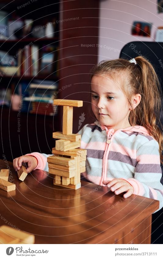Little girl preschooler playing with wooden blocks toy building a tower. Concept of building a house child biulding brick education game creativity concept