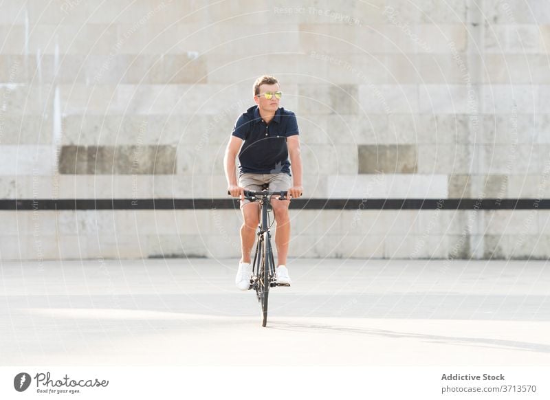 Young man riding bicycle on the street adult bike blond casual caucasian copy space ride cycling cyclist lifestyle male millennial mobility modern people