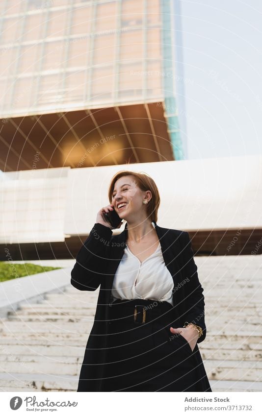 Delighted businesswoman talking on smartphone on street discuss work walk city manager using female chat conversation connection communicate elegant suit