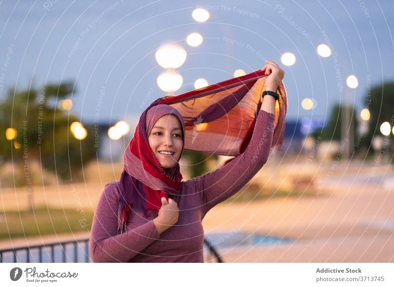 Smiling Arab woman in hijab on street put on muslim religious city evening headdress content female ethnic arab smile happy style glad delight joy relax