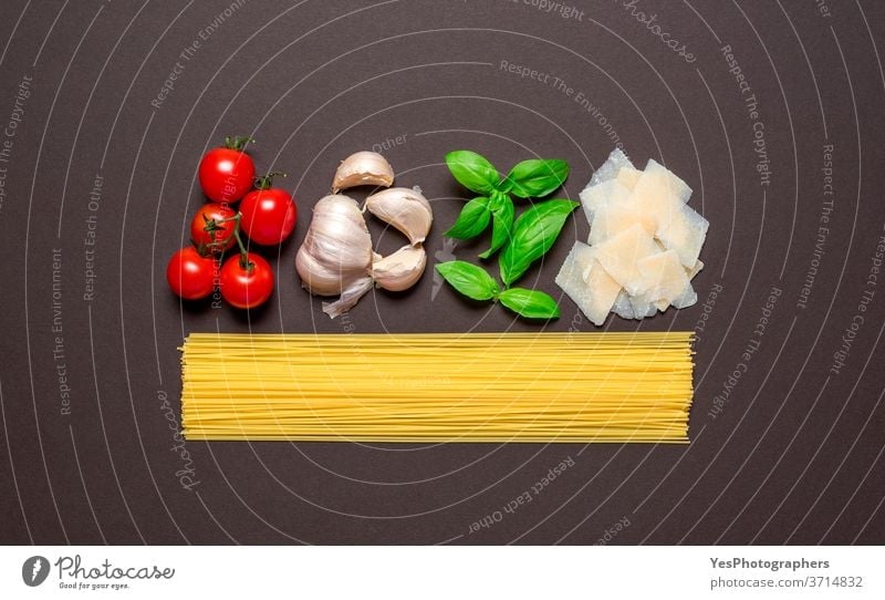 Spaghetti and the sauce ingredients, top view. Uncooked pasta isolated brown colored table. above view aligned background basil carbohydrate carbs cheese