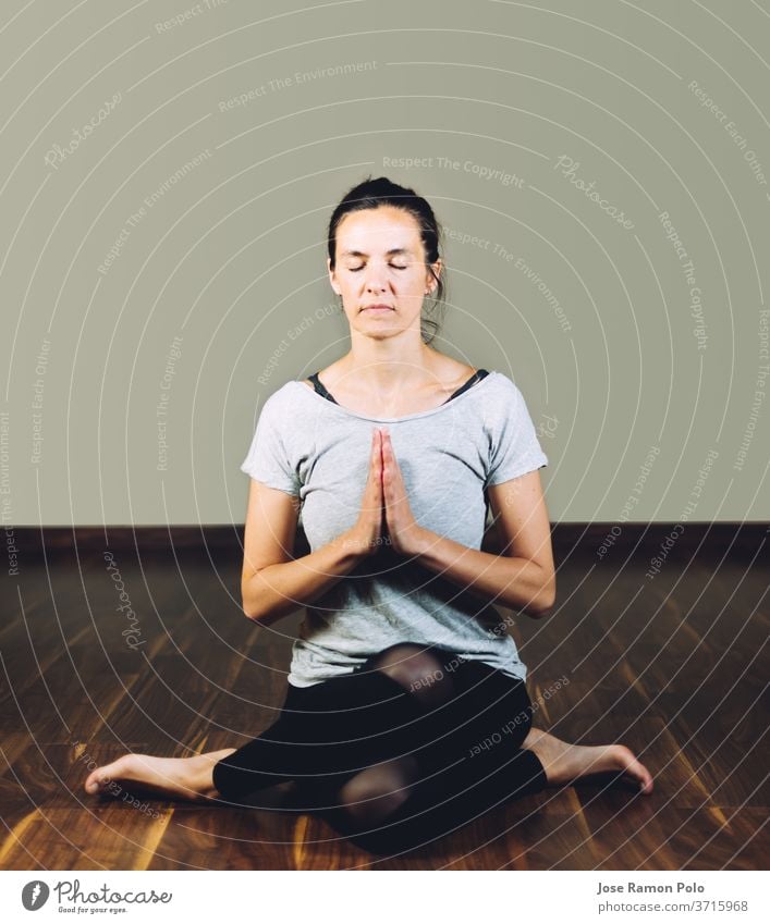 Woman sitting cross-legged on the floor doing yoga relaxation exercises. Concept of healthy living and yoga exercising people meditating women flexibility