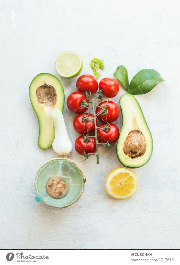 Fresh salad ingredients. Halves avocado, tomatoes, lemon and olives oil on a white background. Top view. Vegetarian food. Healthy eating fresh halves avocado