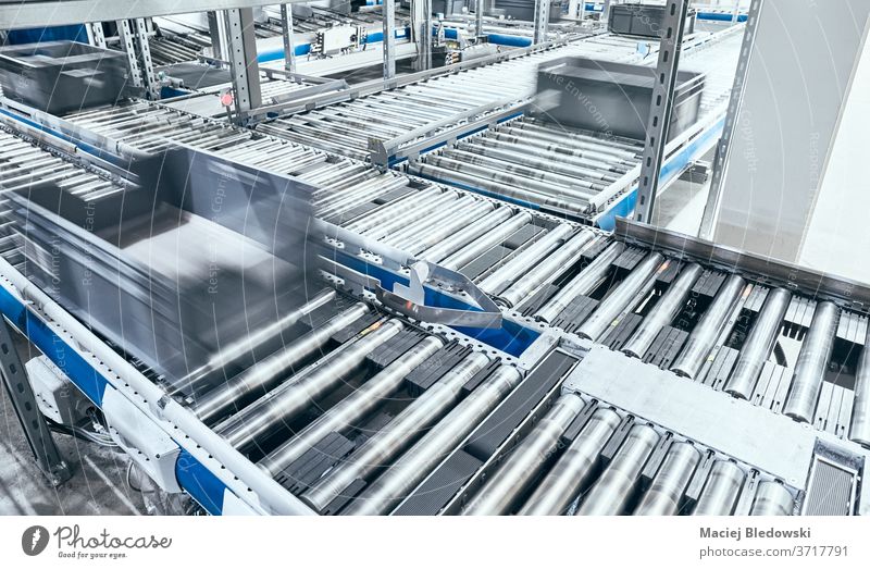 Modern roller conveyor system with boxes in motion. belt automated factory line logistics distribution center production warehouse manufacturing industry plant