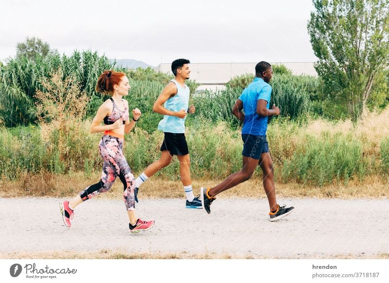 Three friends exercising outdoors, running in rural setting sport three people young men young women athlete vitality motion togetherness friendship female