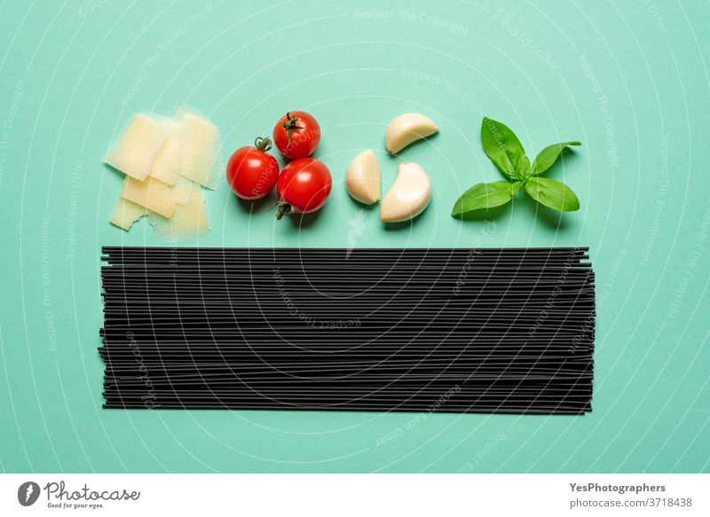 Black spaghetti and sauce ingredients top view. Uncooked pasta isolated on a green background above view aligned basil black black spaghetti carbohydrate carbs