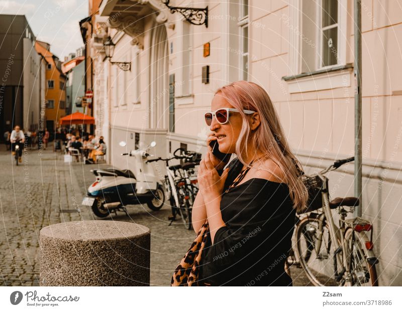 Young woman in the city centre of Regensburg on the phone Bavaria Seeightsing Leopard print sunglasses Summer Sun Fashion fashion design Colour photo