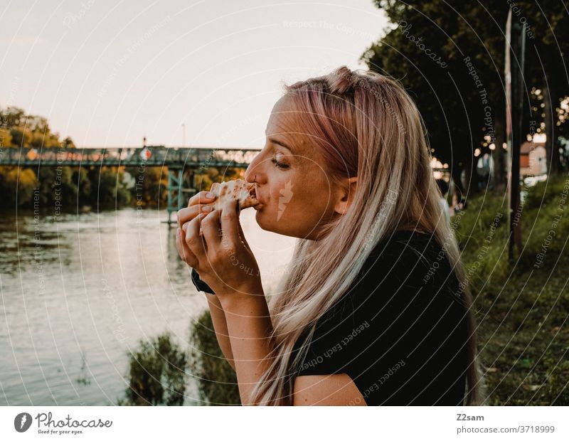 Young woman eating pizza on the banks of the Danube Eating food Fast food Pizza hunger Lunch Food Dinner Nutrition outdoor Regensburg Water Summer vacation