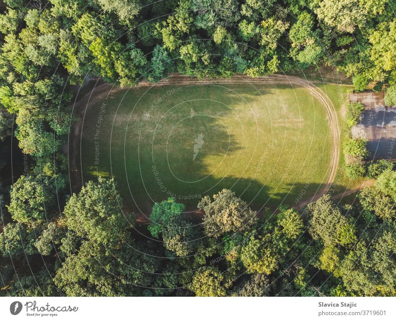 Aerial View of empty field with trim path  in a dense forest above aerial background court courts day design exercises fitness foliage football frame grass