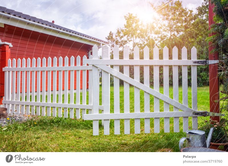 White picket fence i an idyllic garden sweden countryside foliage shrub bush grass life peaceful spring bloom sun lawn summer backyard outdoors entrance green