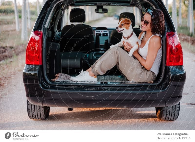 young happy woman in a car cuddling her cute dog. Travel concept travel jack russell together love outdoors lifestyle friendship vacation animal breed tender